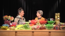 two women talking with a table full of candy in front